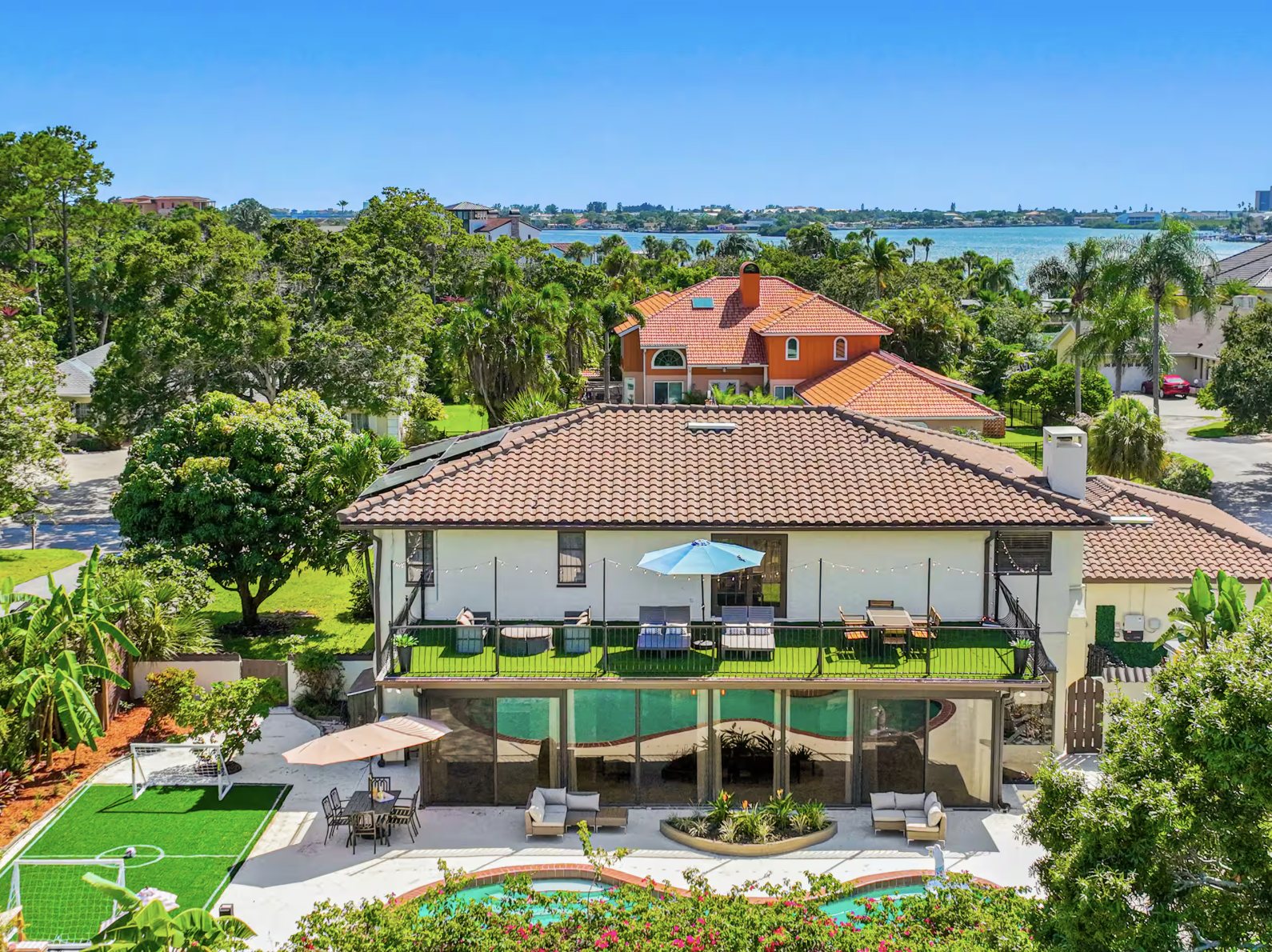 The back of the estate from the air: covered balcony, pool deck, and the water beyond